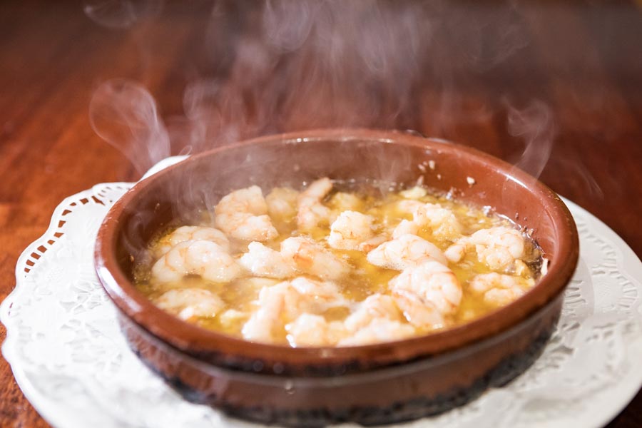 Gamberi sgusciati in casseuola di terracotta con aglio e peperoncino, cucinati con vino di Jerez