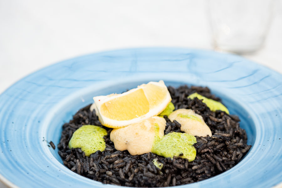 Paella di riso nero con calamari con salsa di inchiostro e aioli