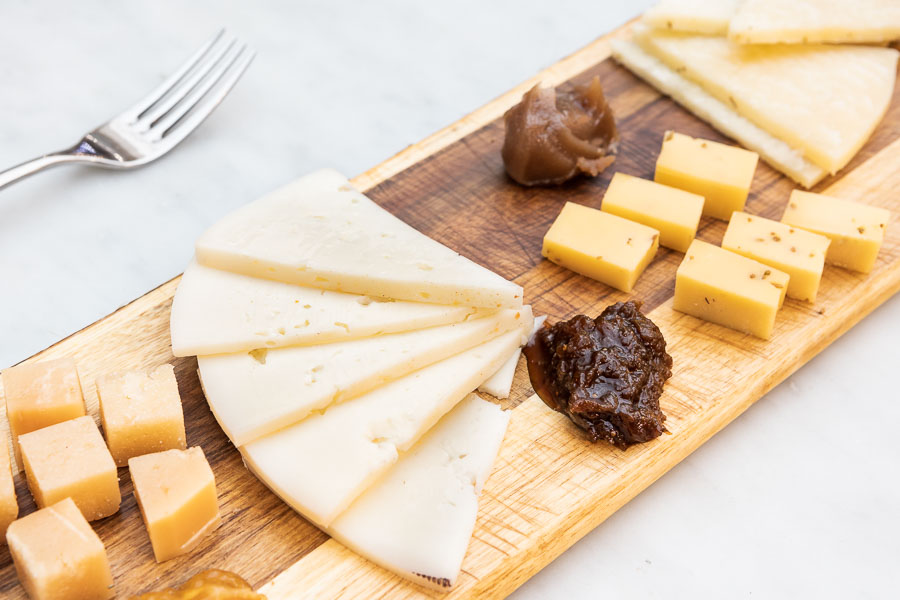 Tabla de cuatro tipos de queso y cuatro tipos de mermelada