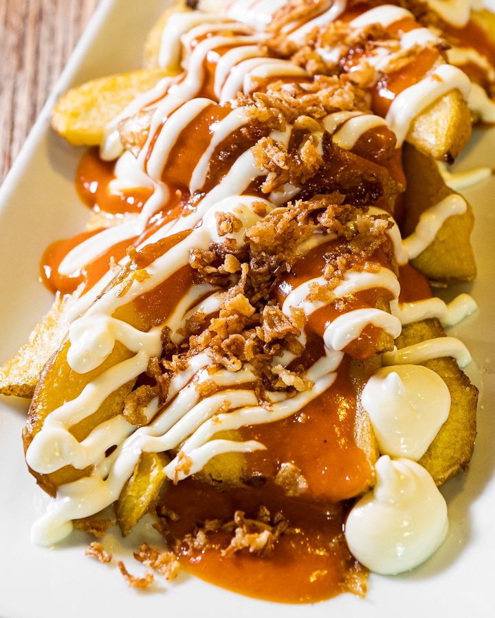 French fries with spicy sauce, garlic mayonnaise (ali-oli sauce) and fried onion