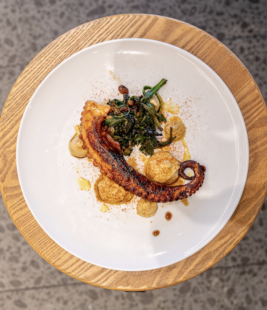 Roasted octopus leg with hummus and sautéed spinach, raisins and pine nuts