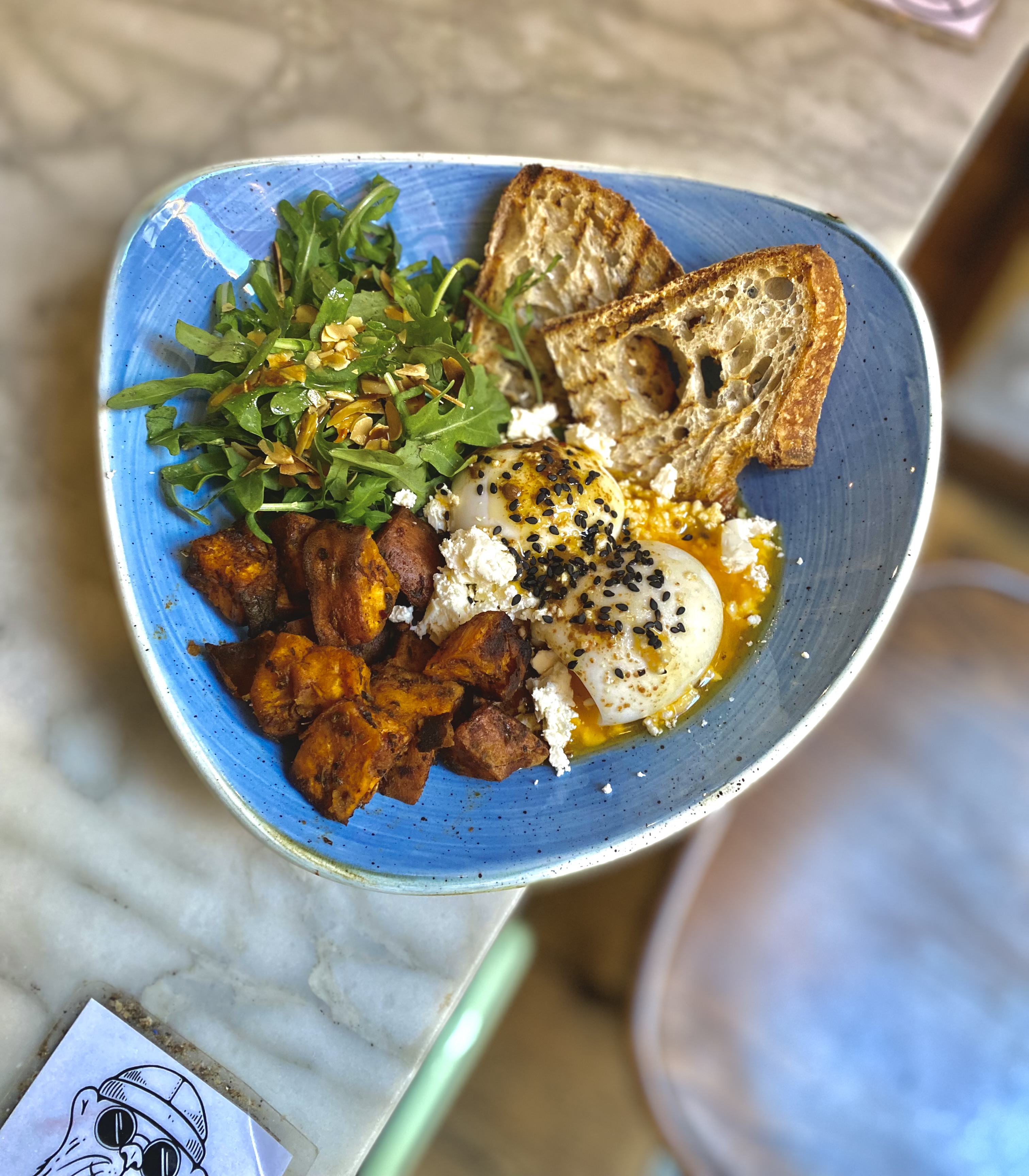 TURKISH EGGS: Greek yogurt bowl with two poached eggs, arugula, roasted sweet potato, paprika sauce, queso feta. Served with toasted sourdough bread.
