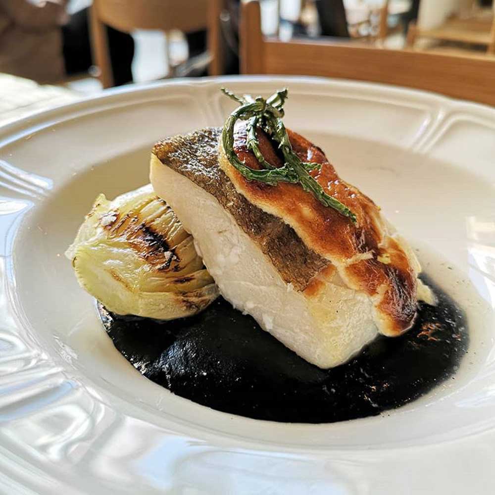 Codfish gratin with ink sauce and roasted lettuce heart 